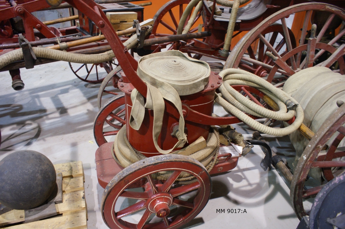 Brandspruta på tvåhjulig kärra för handkraft
( 6 man ). Av järnplåt och trä. Från mitten av 1800-talet.  Har från senare delen av 1800-talet tillhört Laboratorieholmen, Karlskrona.
Sprutan ovalformad, rödmålad, med två pumparmar av järn, kopplad till sprutan. På hävarmarna tvärsgående trähandtag. Sprutan  fast till kärra, rödmålad, vars hjul är beslagna med ringar av järn, tjänstgörande som stöd, då sprutan är uppställd för pumpning. På vardera sidan av flaket en draglina.