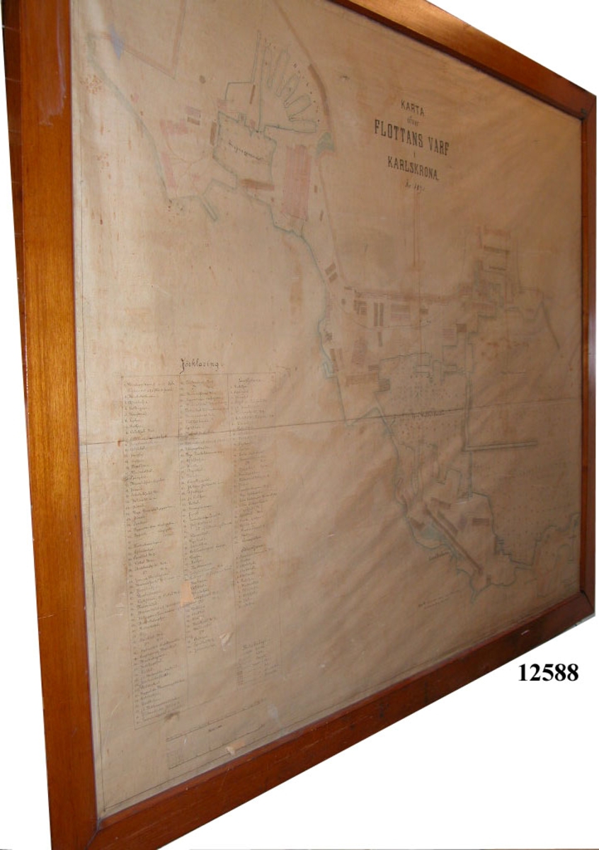 Karta ritad på väv och färglagd.
Text: Karta över Flottans Varf i Karlskrona 1895.
Inom glas och ram.
