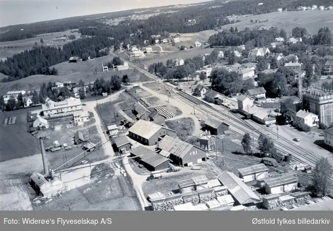 Rakkestad Sag og Høvleri ved Rakkestad sentrum, skråfoto 23. juni 1959.
Midt i høyre billdekant kan en se at den første kornsiloen i Rakkestad er under bygging.
