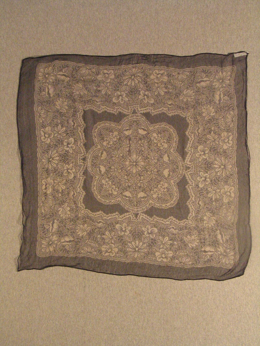 Stort blomstrefelt, utforma som ein blondeserviett, i midten. Breitt felt med same typen dekor rundt "servietten".