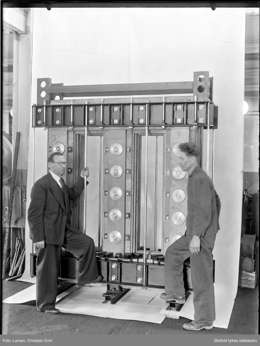 Produktfoto av transformator, 1945, ukjent fabrikk og ukjent sted i Sarpsborgdistriktet. Ukjent mann i kjeledress og ukjent mann i dress..


Arne Andersen 2013: Kan dette bildet ha sammenheng med objektet
ØFB.CLA.UNR.00917 ?