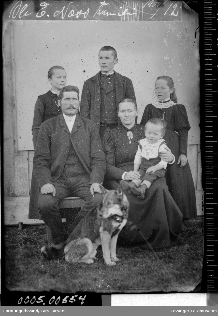 Gruppebilde av to menn, to kvinner, to barn og en hund.