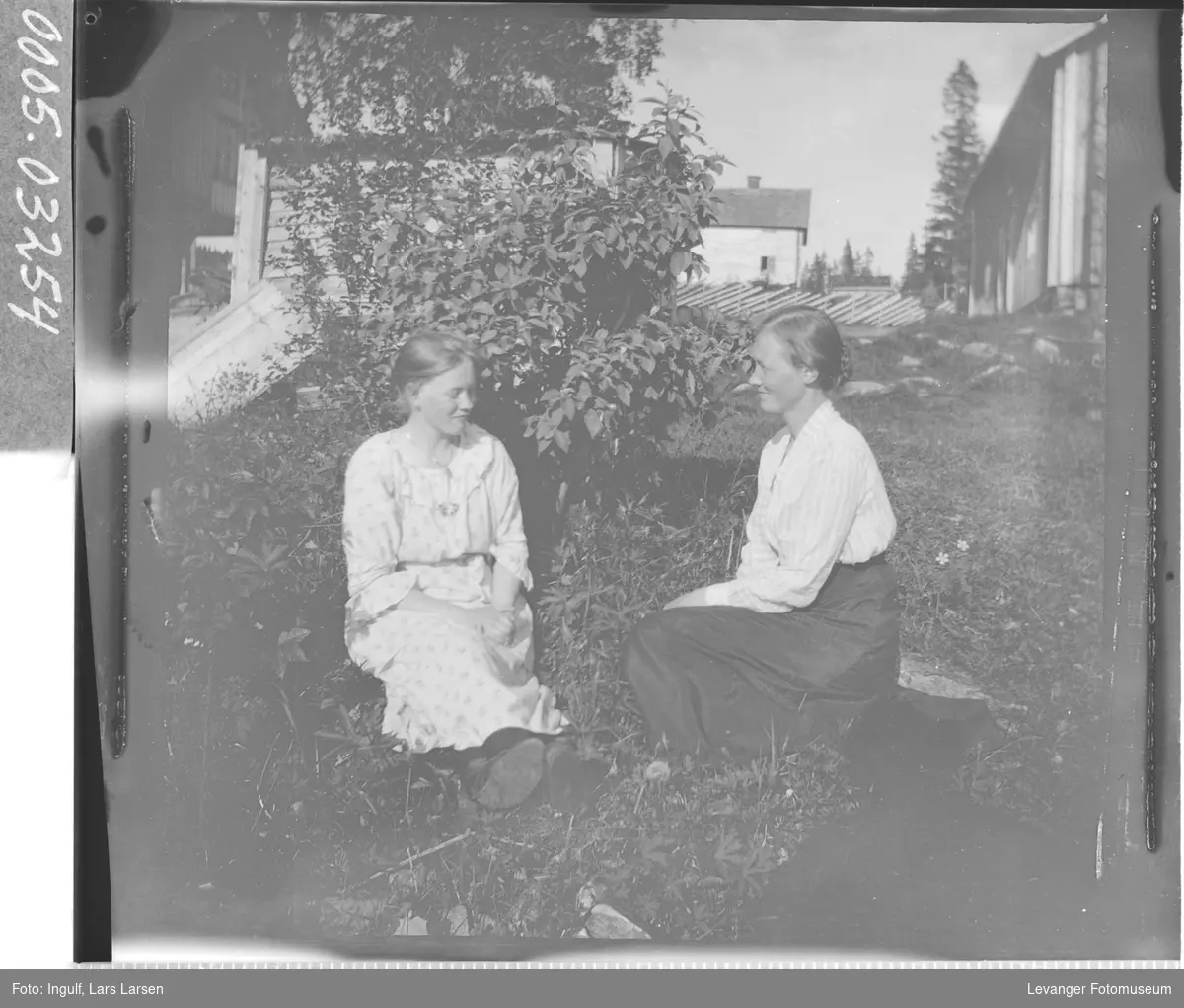 Portrett av to kvinner som sitter i gresset.