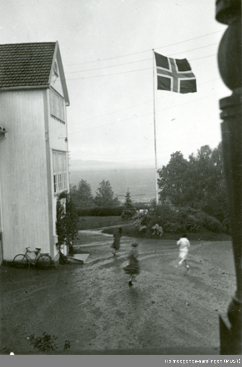 Noen springer over en gårdsplass i noe som ser ut som et fryktelig regnvær. "Viken juli 1935".