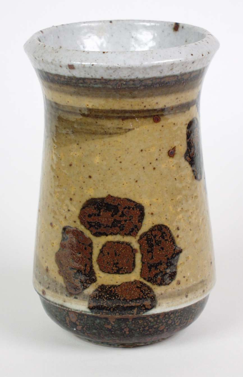 Kraftig beige og brun vase i steingods med saltglasur.
Stiliserte blomstermotiv rundt vasen.