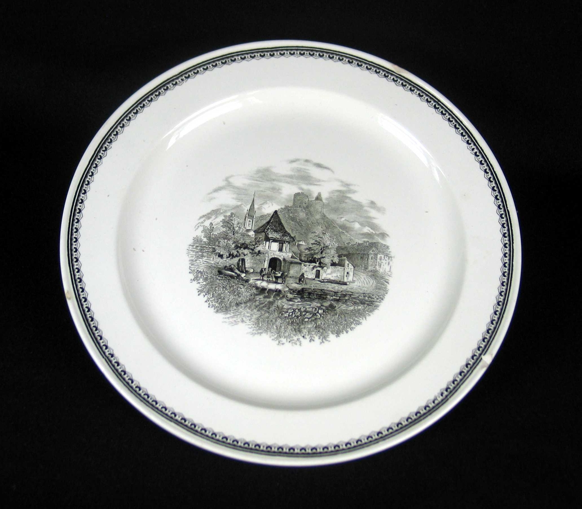 Rundt serveringsfat i offwhite keramikk med sort dekor.
