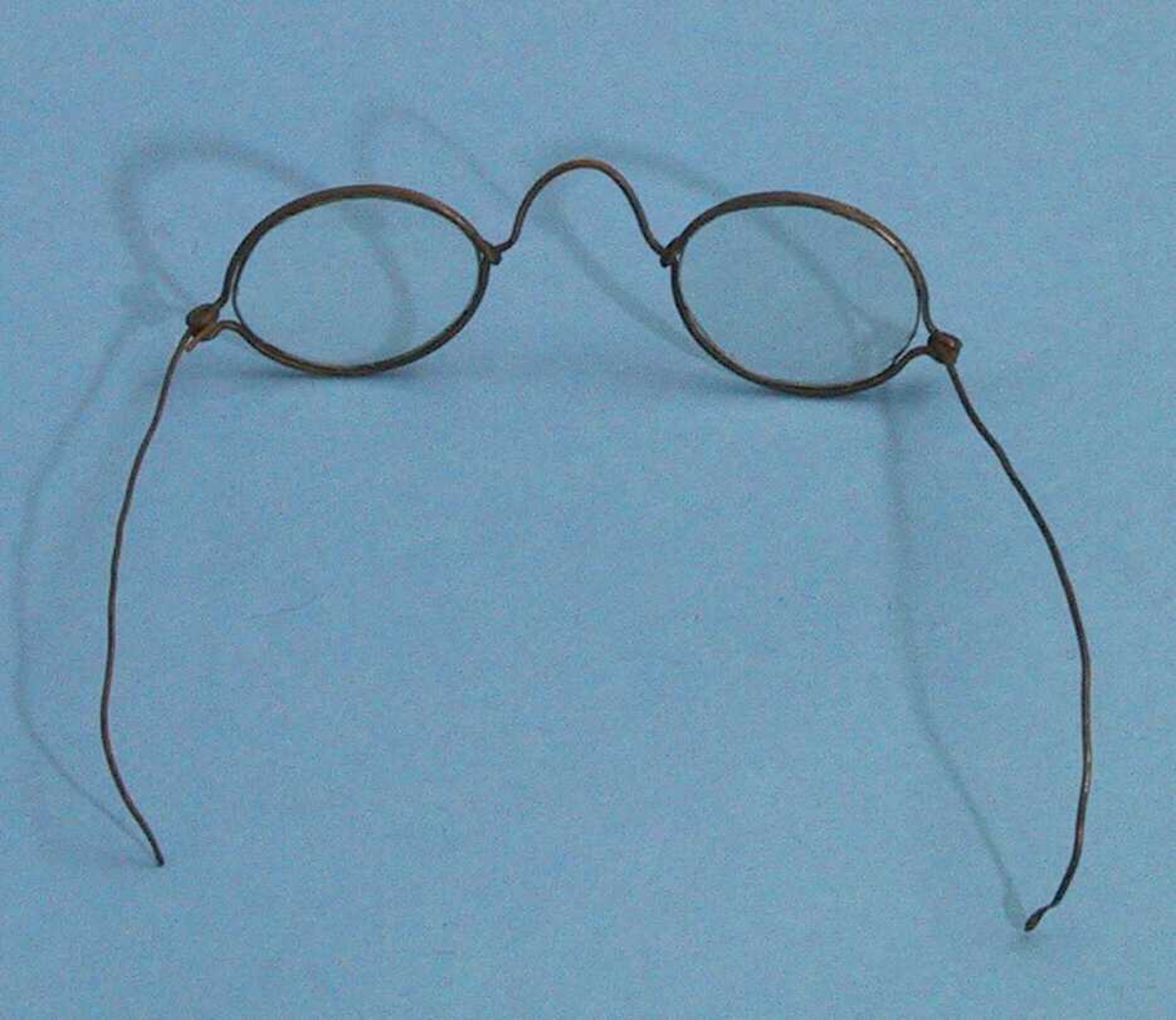 Enkle briller, brilleglassene er små, omfatningen er laget av ståltrådliknende materiale og lett bøyelig.