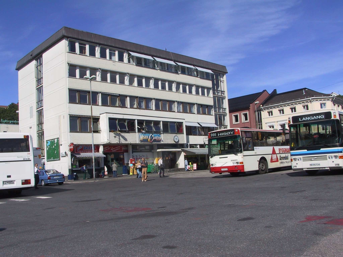 Rutebilstasjonen i Arendal, bygningen i bakgrunnen, busser til venstre og til høyre. 