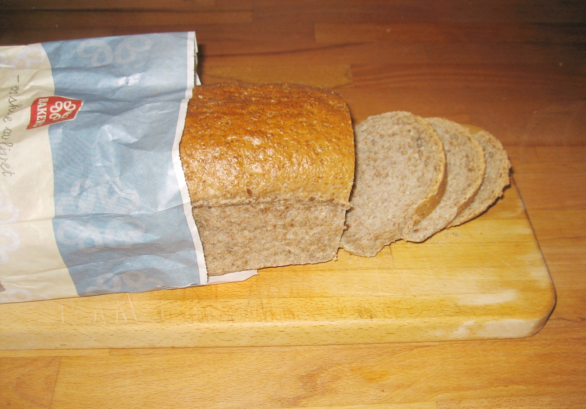 Motivet på brødposen et brød med tre oppskårne brødskiver og noen kornaks