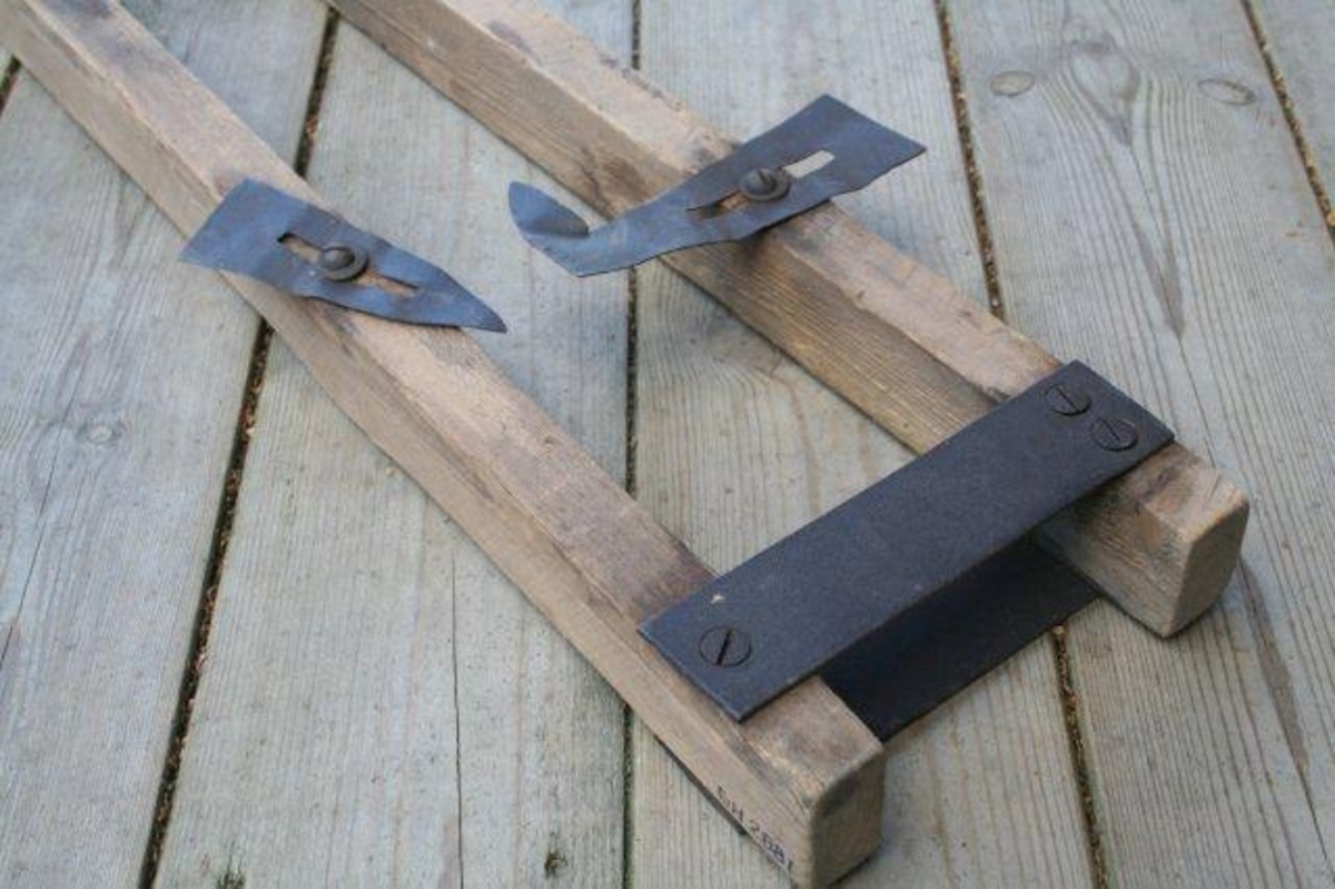 To trelekter forbundet med to flate jernstykker i ene ende og bolt i andre ende. På lektene er montert justerbare jernplatedeler.