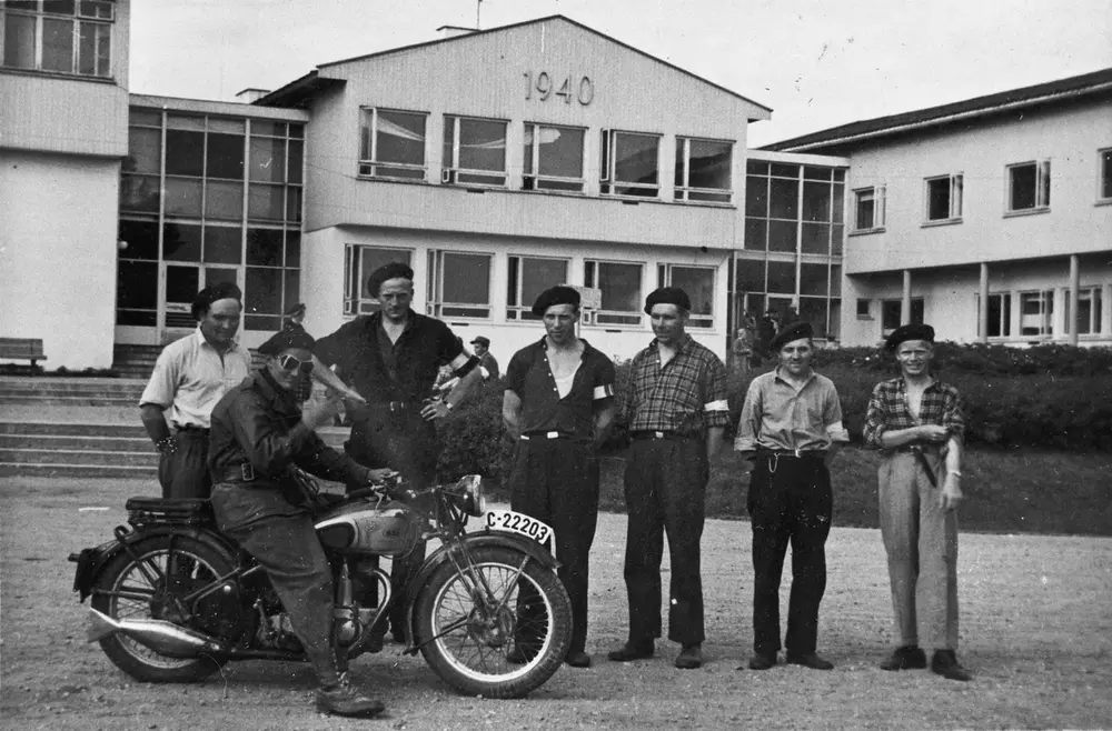 Hjemmestyrker utenfor Romerike Folkehøyskole. Motorsykkelen er en BSA – modell som kom i 1937.