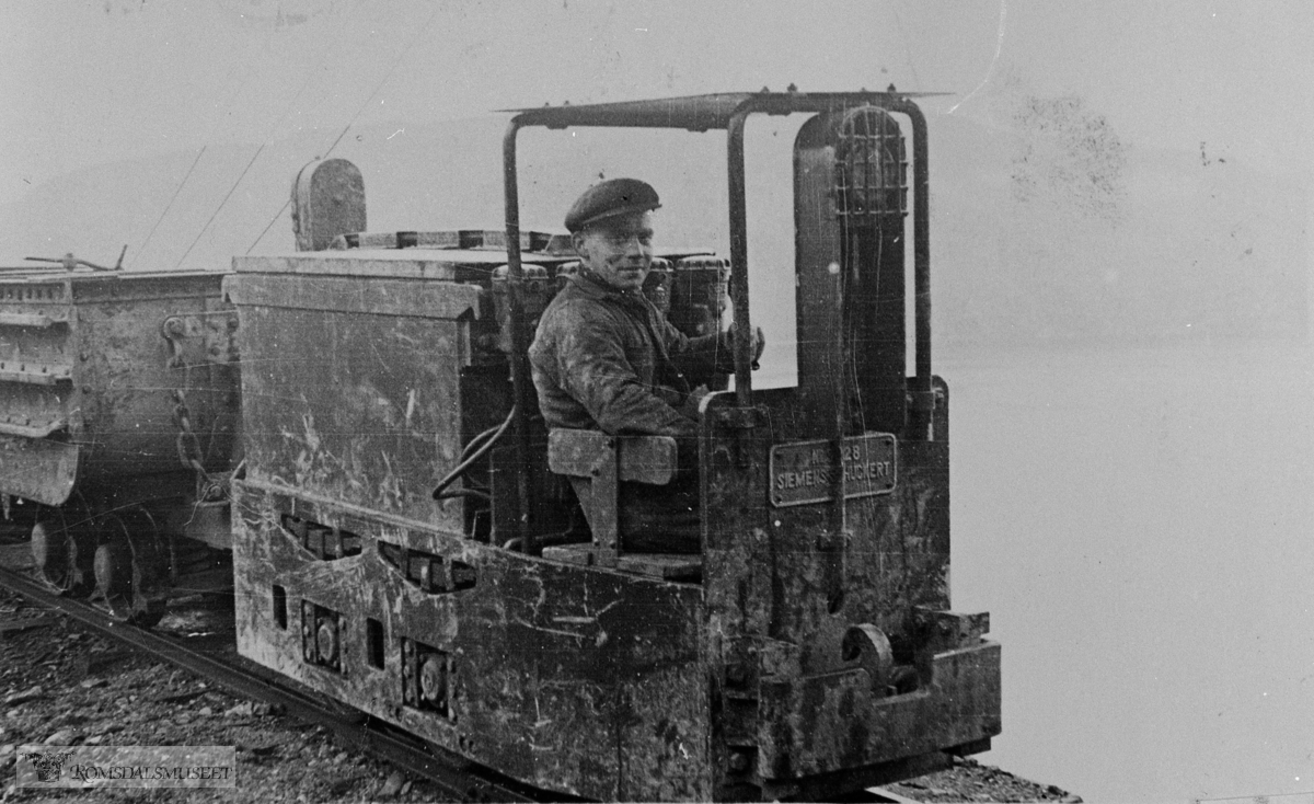 Rødsand Gruber. Hermann Bugge kjører elektrisk lokomotiv..Lokomotivet må ut fra skiltet være Siemens-Schukert nr. 5428, et akkumulatorlokomotiv som var nytt i 1952.