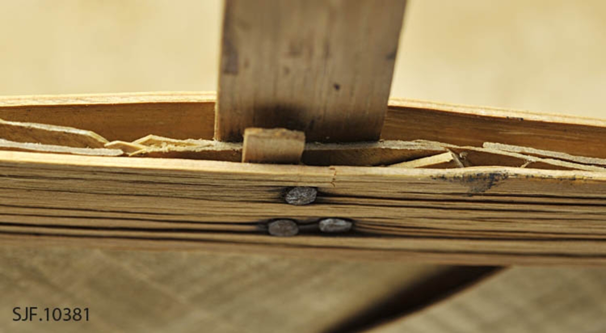 Sponkurven er skråflettet, og har en bøyd hank. Sponene er jevnbrede, og er maskinhøvlet.

Bunnen har en rektangulær form. Sponene er vikt opp, og sidene er rette. 
Kanten danner en form tilsvarende bunnen. På kanten er det lagt på et smalere spon på hver side som er festet med metallstift. 

Innvendig og utvendig skjøt ligger på hver sin kortside.
Hanken ligger på innsiden av de flettede sidene, og er festet mellom flettet side og indre kantspon. Hanken består av et tykkere spon som delvis er kløyvd i to. Spiker og stifter i kurvkant er rustne.

Kurven har tydlige spor etter jordslag. 

Det ligger et dobbelt gråpapir i bunnen på kurven.
