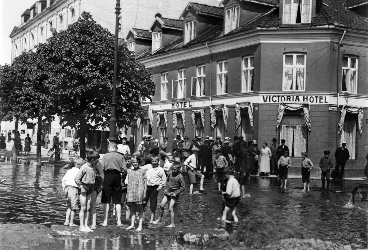 Mjøsflom, storflom i Mjøsa 1927. Barn leker i flomvannet i Strandgata, Hamar. Victoria hotell, Strandgata 21.
