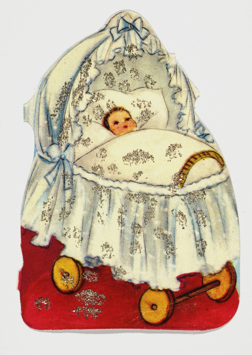 En dukke ligger i en dukkevogn med kappe.