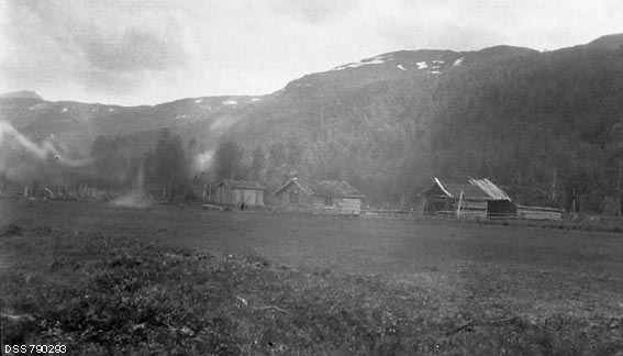 Gardsbruket Kjosmo i Målselv i Troms.  Fotografiet viser tunet, med et lite våningshus og to uthus, omgitt av engarealer.  I bakgrunnen en kraftig fjellrygg med skogvegetasjon nederst i liene, skogbart terreng med snøflekker høyere oppe.

Kjosmo var en av to eiendommer som ble fradelt den statseide Malangsallmenningen i 1907, og som to år seinere ble solgt til private brukere.  Dette fotografiet er tatt seks år etter den nevnte skylddelinga.  Ikke korrekturleste avskrifter av dokumenter knyttet til Kjosmos fradeling fra den statlige utmarkseiendommen finnes under fanen «Opplysninger».