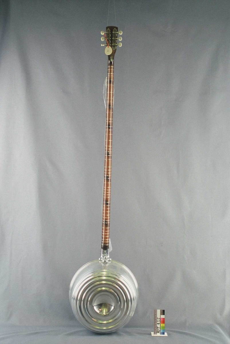 Langhalset strykeinstrument med rund resonanskasse av aluminium.
2 x 3 strenger med bue. Nytt instrument.