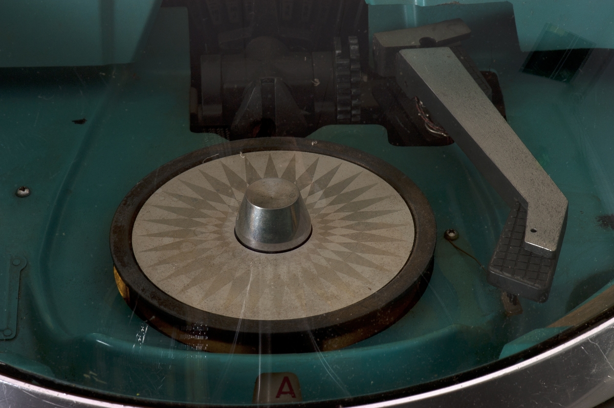 Jukeboks med monolyd. Kan velge manuelt mellom 200 låter fra 100 vinyl-singler ved å dreie på et hjul. Jukeboksen er romstor og tung med en vekt på 155 kg.