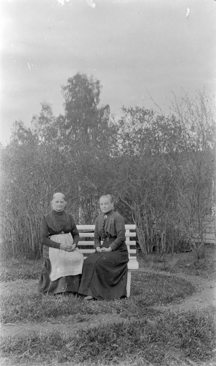 Eldre damer på en benk i hagen på Kise østre, Nes, Hedmark. Tina Skredshoel (1857-1939) og Gunda Tørud.