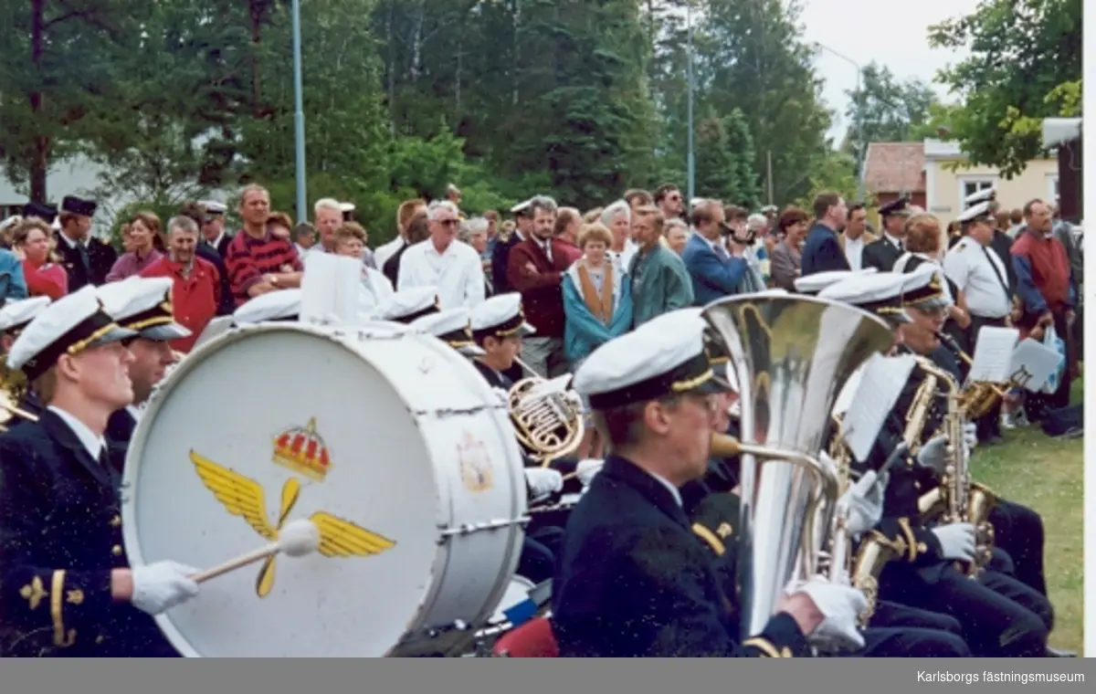 F6 Karlsborg 1994. Nedläggning av förbandet. Flygvapnets musikkår, i huvudsak bestående av medlemmar ur Stockholms Symfoniker, spelade marchmusik, s.k. förgaddning, under det att F6-are med anhöriga, f.d. F6-are, hedersgäster, kamratföreningen, karlsborgare m.fl. samlades kring ceremoniplatsen mellan kanslihuset och flaggstången.