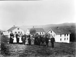 Gruppebilde med 23 personer på gården Stue i Biri; husene i 