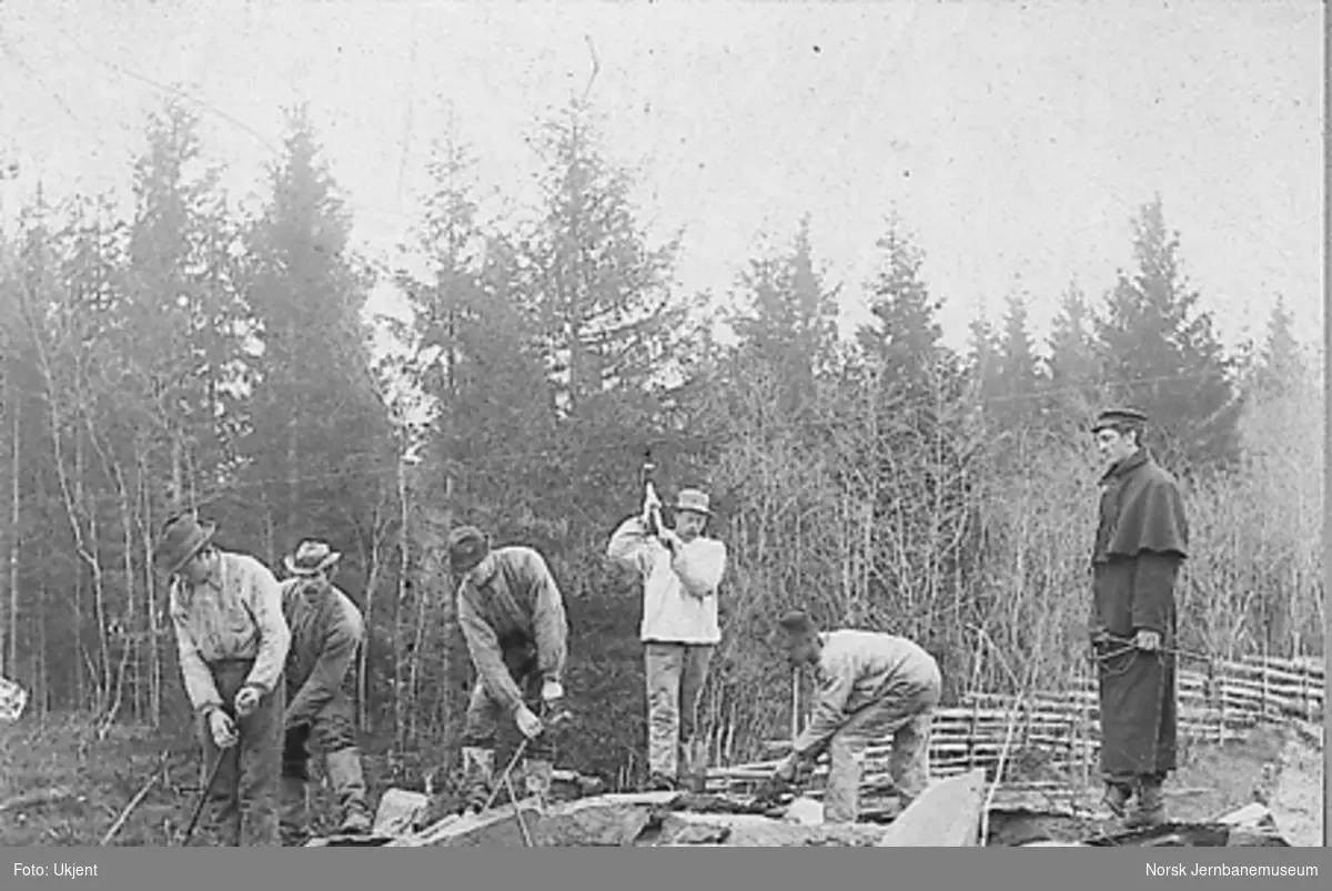 Fem anleggsarbeidere og en oppsynsmann på anlegget av enten Hell-Sunnanbanen eller Eidsvoll-Ottabanen i Gudbrandsdalen