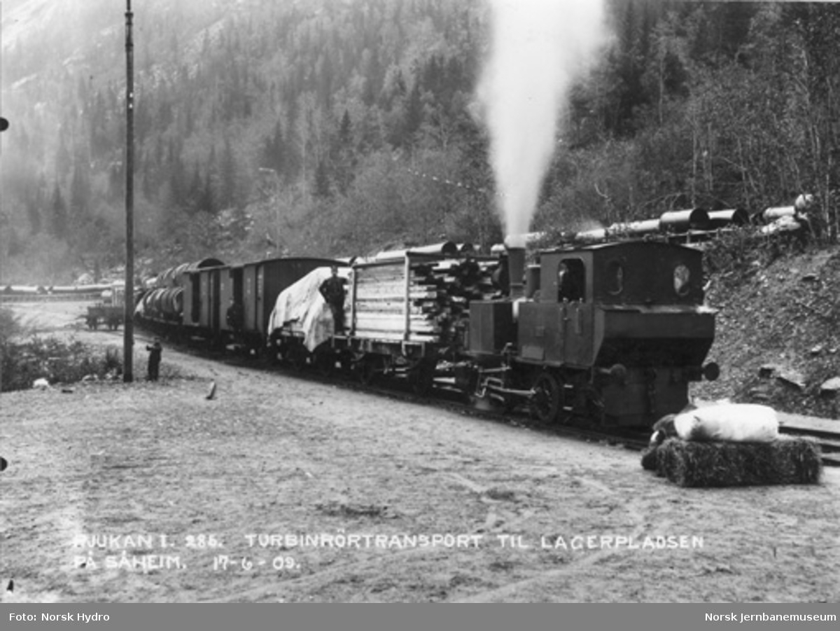 Rjukanbanens damplokomotiv "Odin" foran godstog, blant annet med turbinrør, på Rjukan