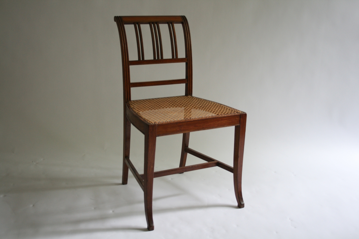 Spinkel stol i mahogni, med rottingsete, smale spiler i ryggen. 5 stoler og 1 kanapé