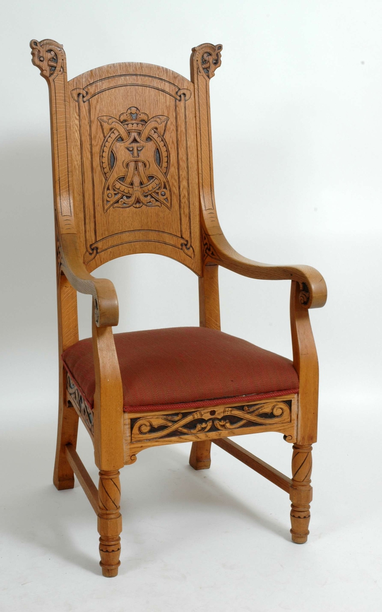 Trestol med armlener, rødt setetrekk og svartmalte trekjæriinger i dragestil. Pyntebånd langs polstringen.