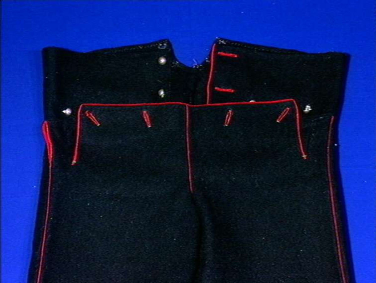 Svarte bukser med rød kanting av ull.