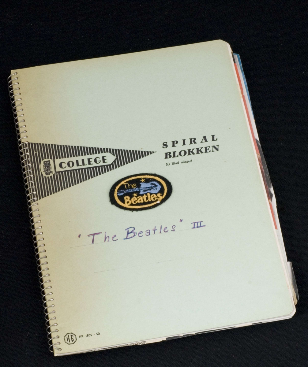 Spiralblokk med ulinjerte ark. Innlimte klipp fra tidsskrifter og aviser om popgruppen Beatles på 1960-tallet. Håndnummererte sidetall og håndskrevne kommentarer. Lysegrønne permer av tynn papp.
Håndskrevet med rød og blå kulepenn på forsiden.
Stoffmerke i sort, blått og gult med bilde av en gitar og navnet "The Beatles" klistret til forsiden. 