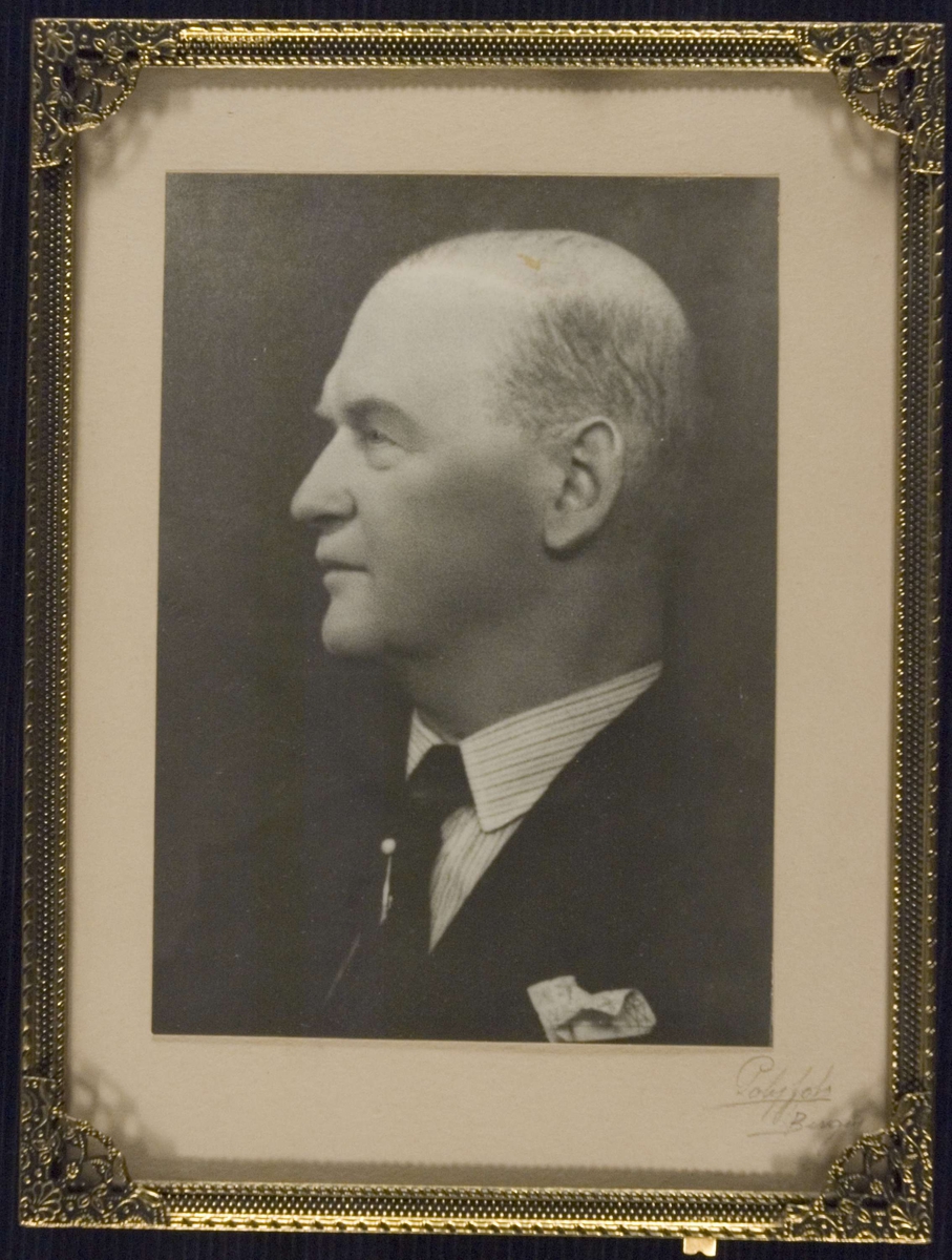 Portrett av apoteker Ole A.M. Heggen. Dress, hvit skjorte og slips. Venstreprofil. Brystbilde.