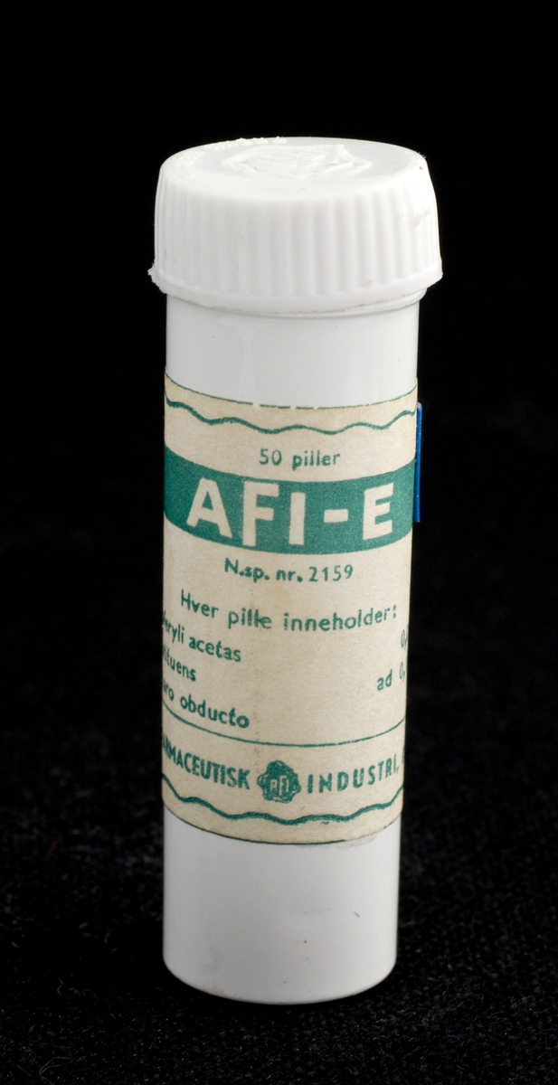 Rund aluminiumsboks med plastlokk med "AFI"-logo. Hvit emaljemaling på boksen og rektangulær hvitaktig papiretikett med grønn trykk. Grønn, bølget pyntekant rundt etiketten.
Lite plastmerke med 5 er festet på hjørnet av etiketten.