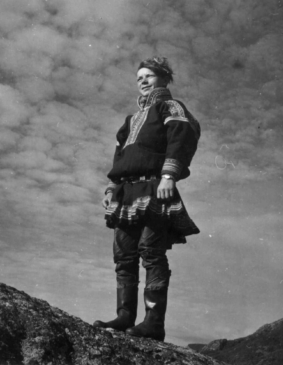 Mikkel Per Kemi i kautokeino-drakt står på fjellet.  Finnmark 1958.