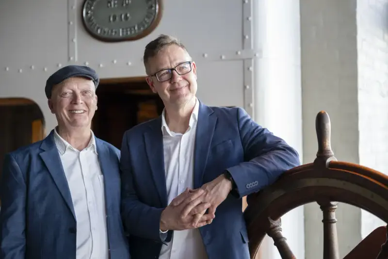 Kunstsamler Matthew Goodheart og førstekonservator Eyvind Bagle, står ved et skipsratt på Norsk Maritimt Museum.
